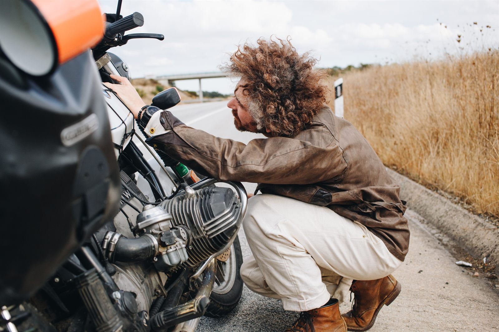 Motard tentant de relancer sa moto en panne au bord de la route