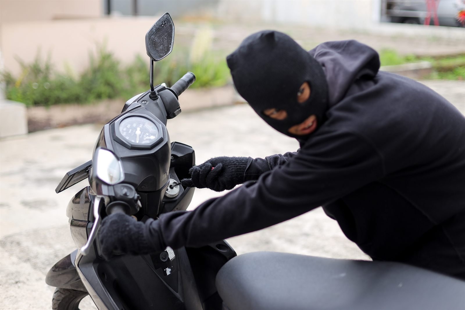 Individu masqué forçant l'antivol d'une moto Individu masqué forçant l'antivol d'une moto