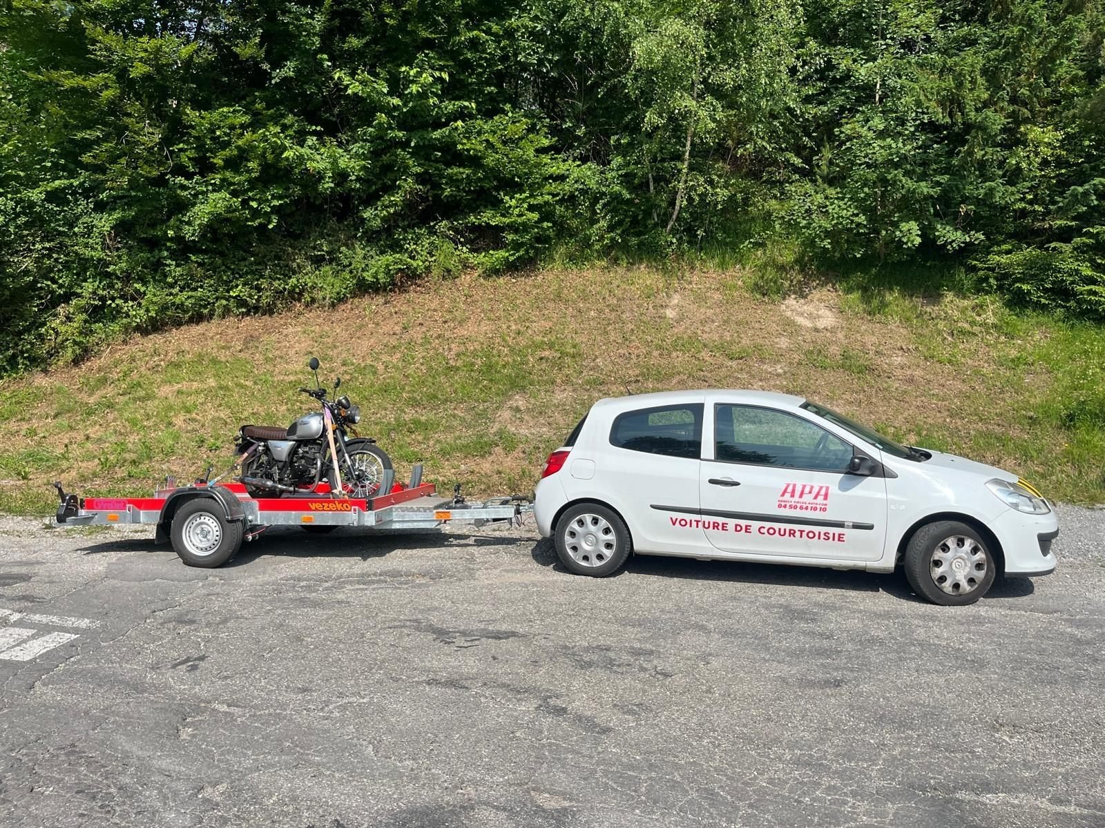 Voiture tractant une remorque porte-moto chargée d'une moto
